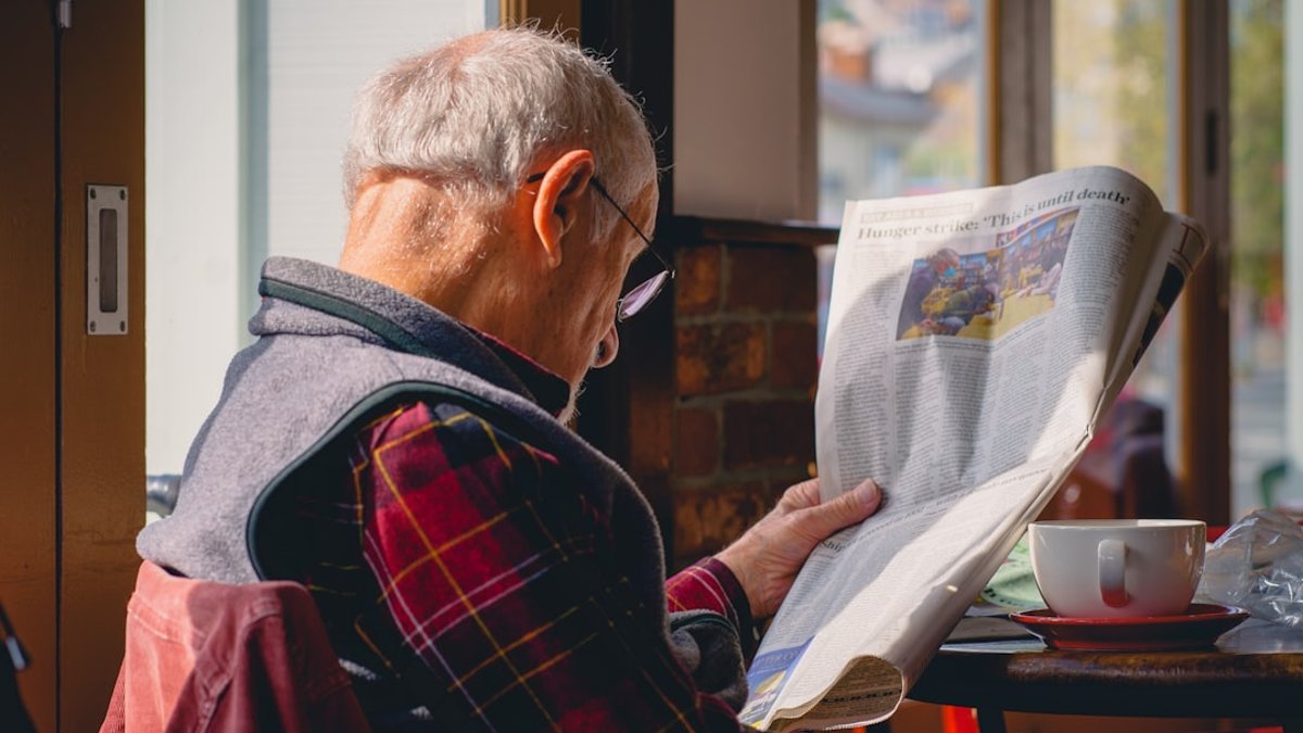 カフェで新聞を読むシニア男性